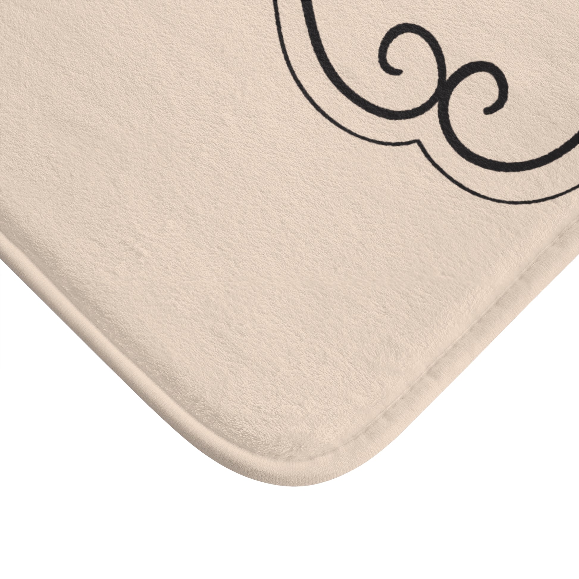 Beige bath mat with a black decorative border on a white background