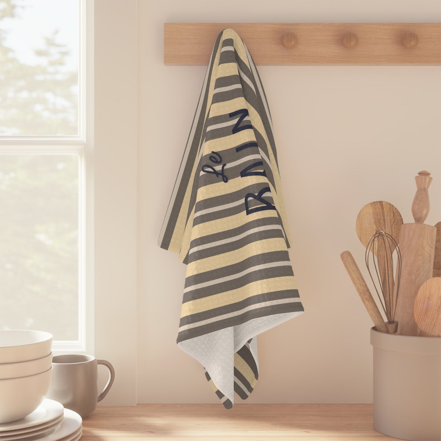 Striped towel with 'Rain' text hanging on a wooden rack in a kitchen.