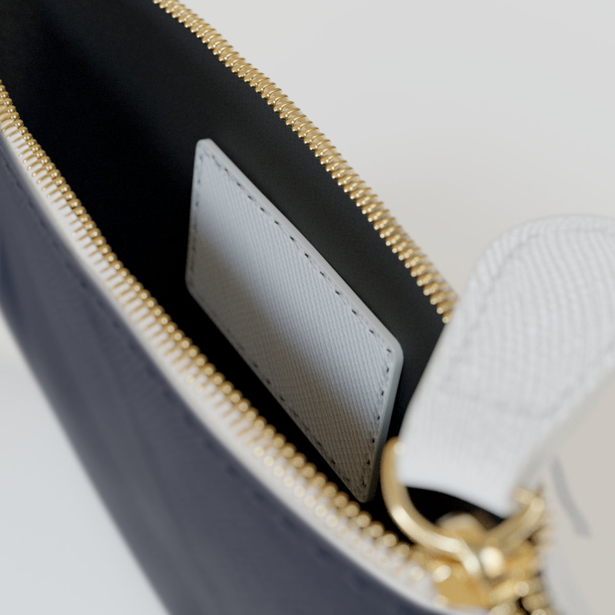 Close-up of a black pouch with pink text and gold zipper on a white background