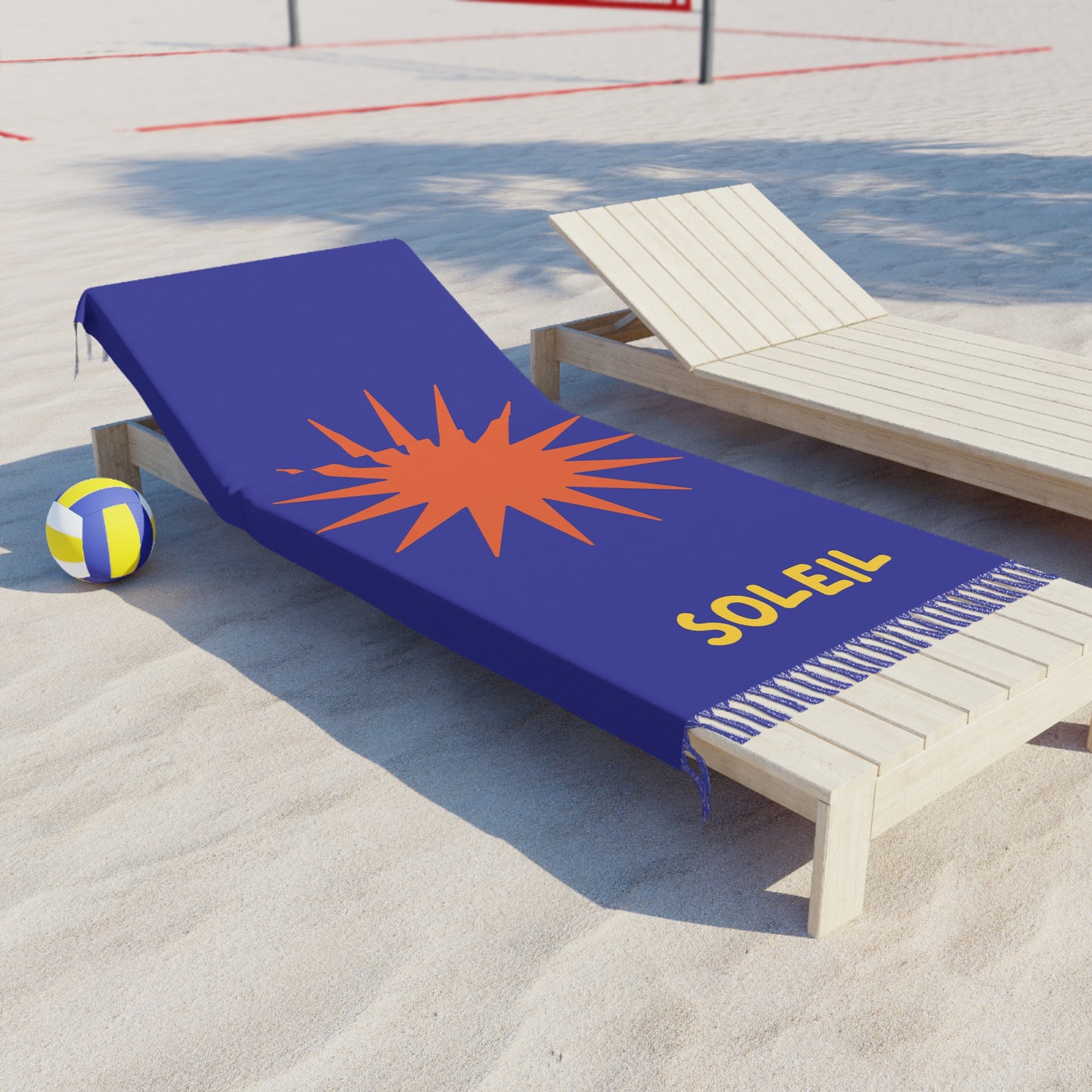 Blue beach towel with orange star design and 'Soleil' text on a sandy beach.
