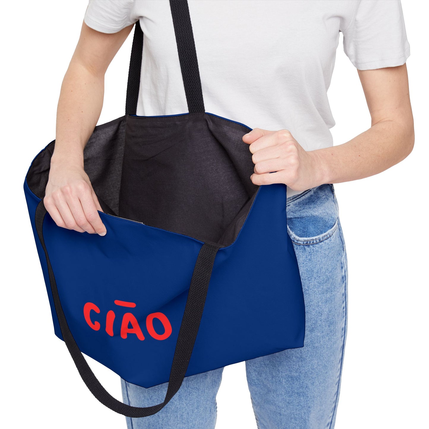 Person holding a blue tote bag with 'CIAO' text, wearing a white shirt and jeans.