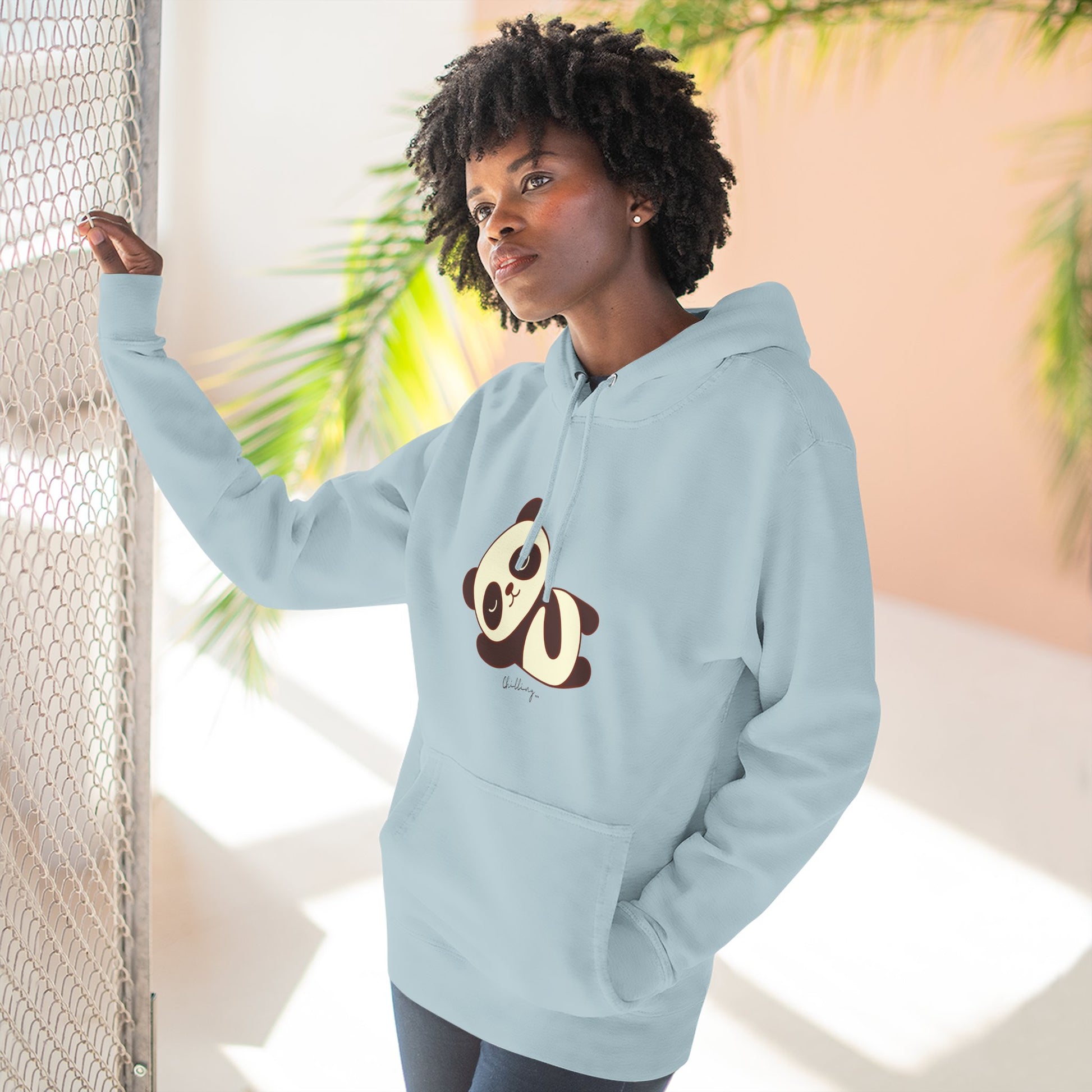 Person wearing a light blue hoodie with a panda design, standing against a neutral background.