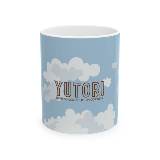 A light blue ceramic mug with a white interior, decorated with white clouds and the text 'YUTORI' and 'JAPANESE CONCEPT OF SPACIOUSNESS' in brown, shown on a white background.