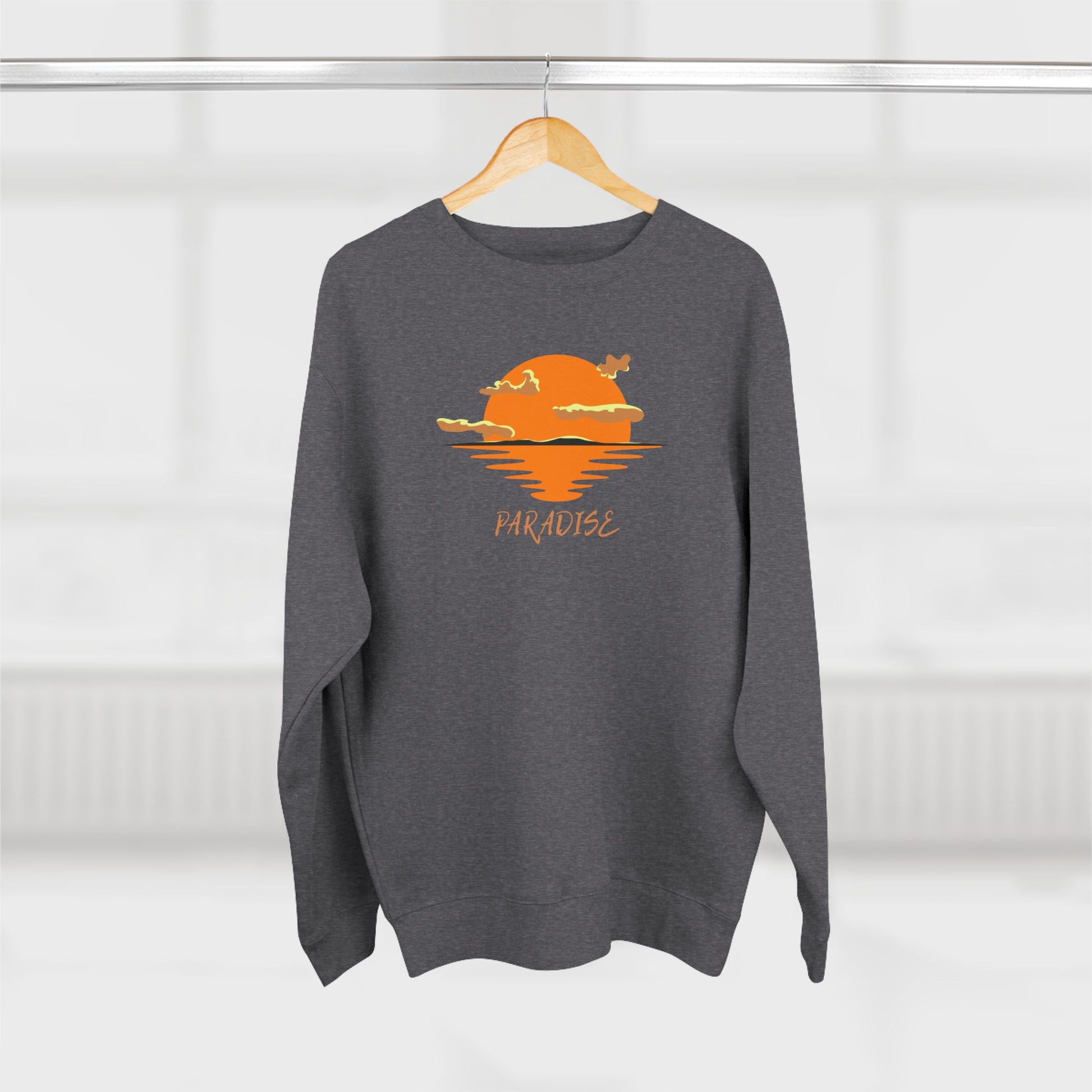 Gray sweatshirt with a sunset design and 'Paradise' text on a hanger against a white background
