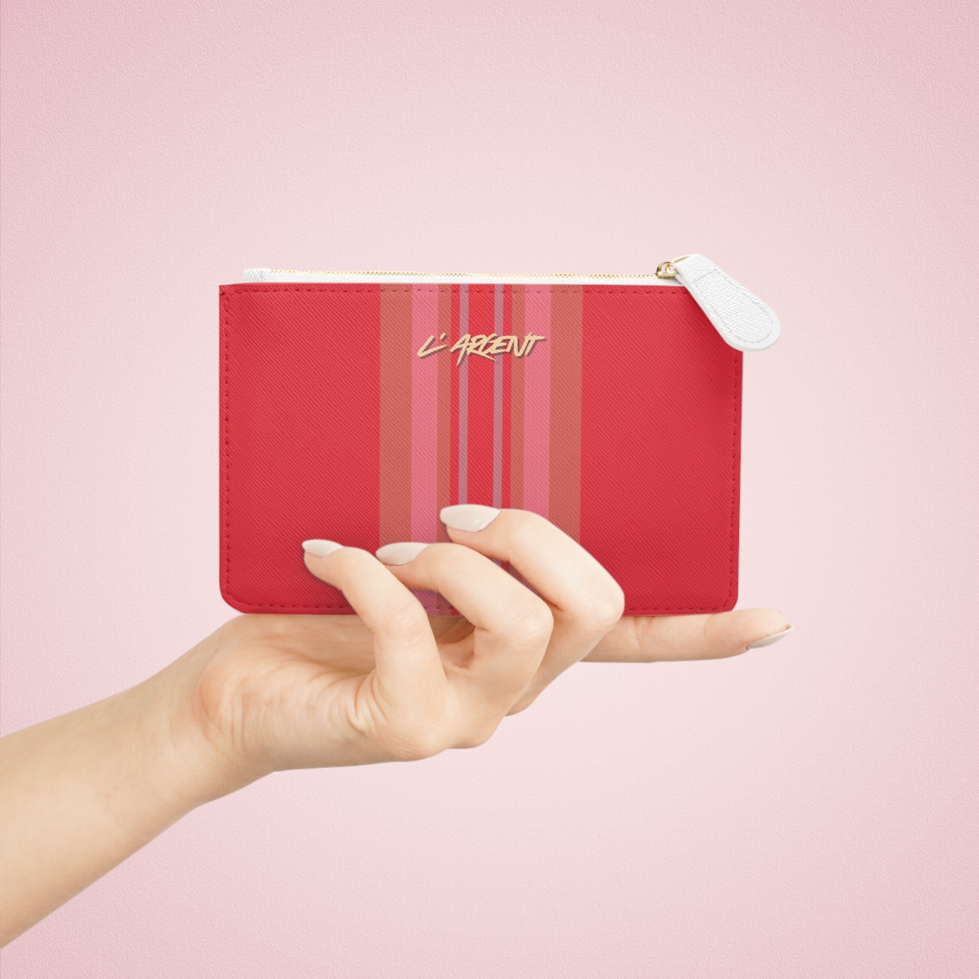 Red pouch with striped pattern and 'L'Argent' text held by a hand against a pink background