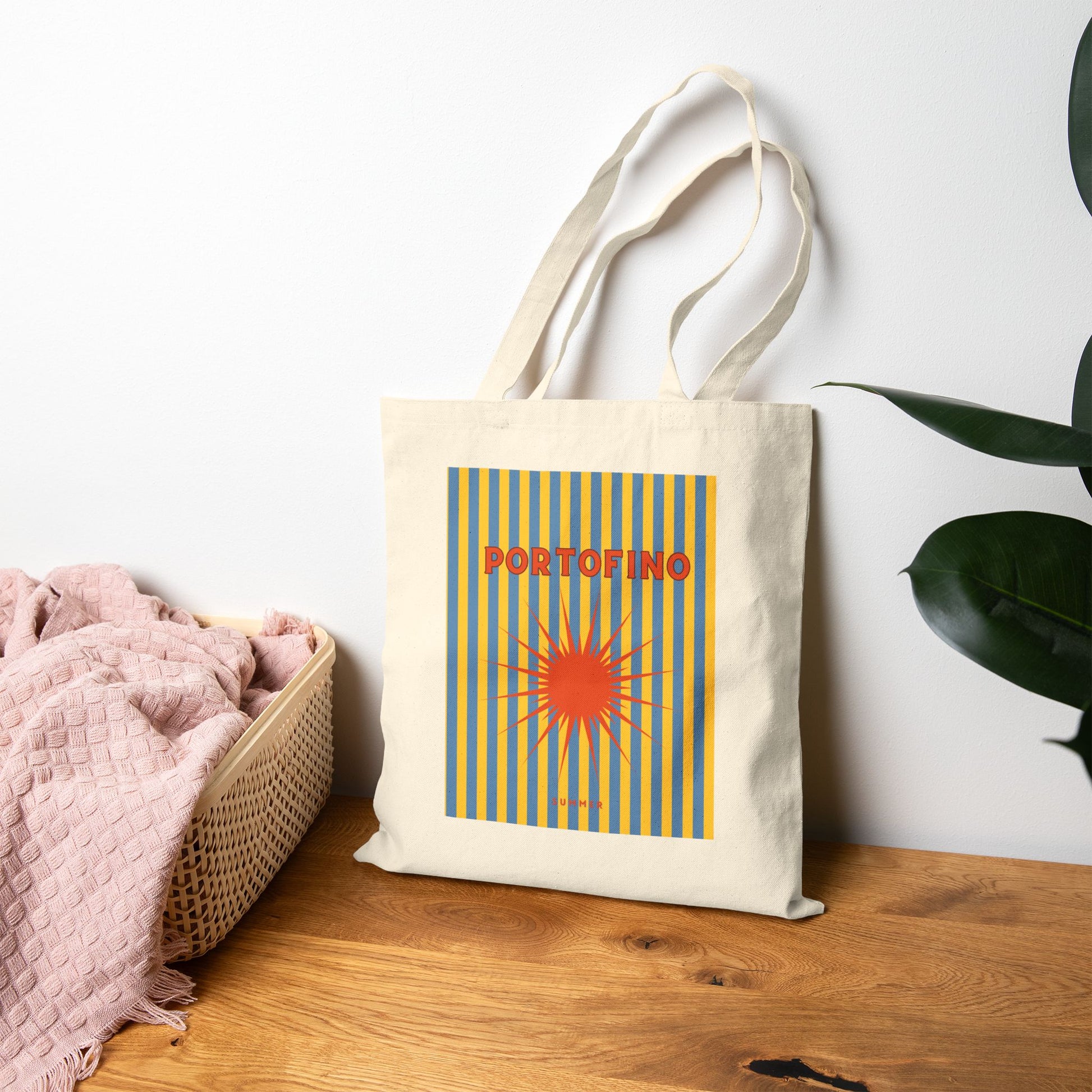 Tote bag with 'Portofino' design on a wooden surface with a white wall background