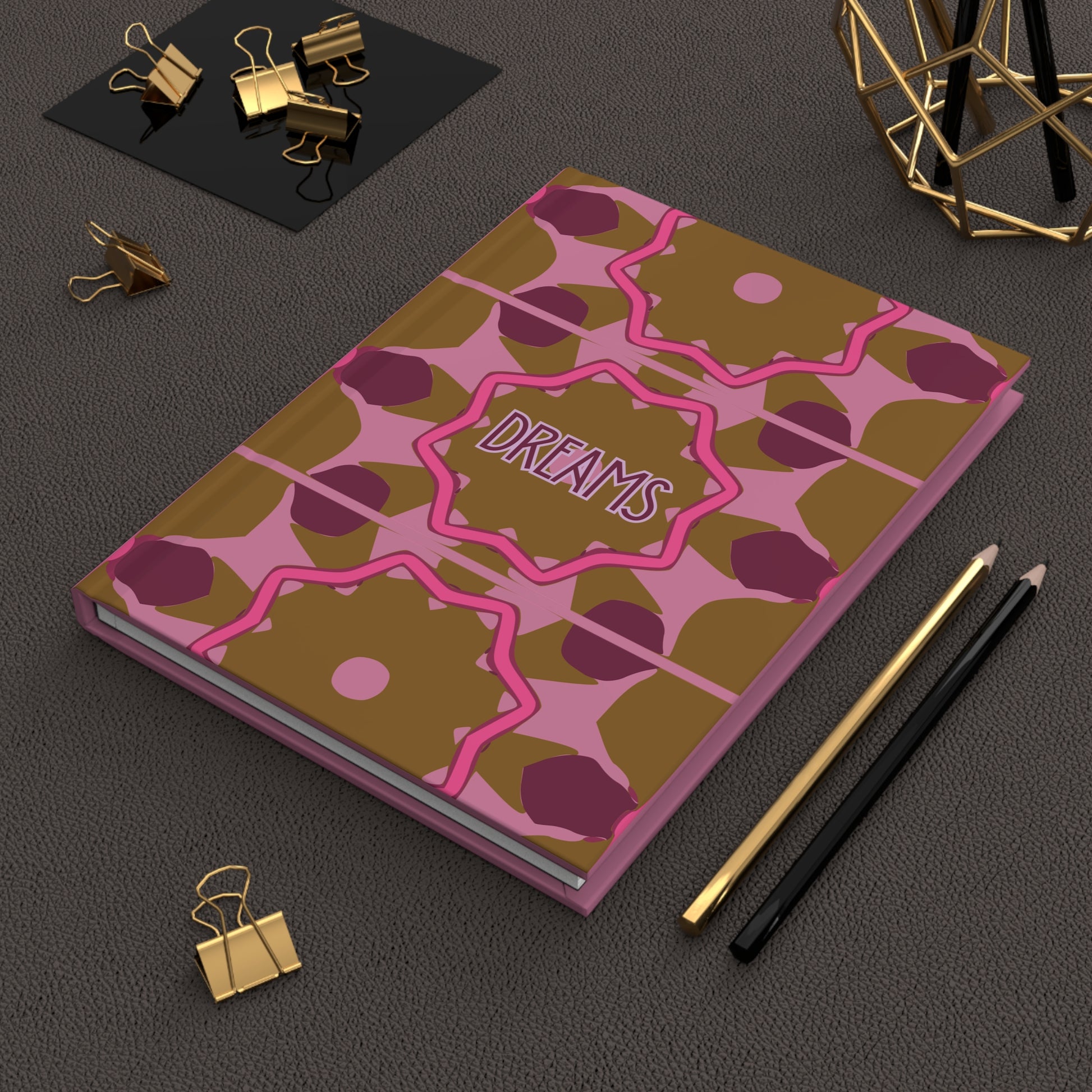 Notebook with decorative cover on a dark surface with stationery items.
