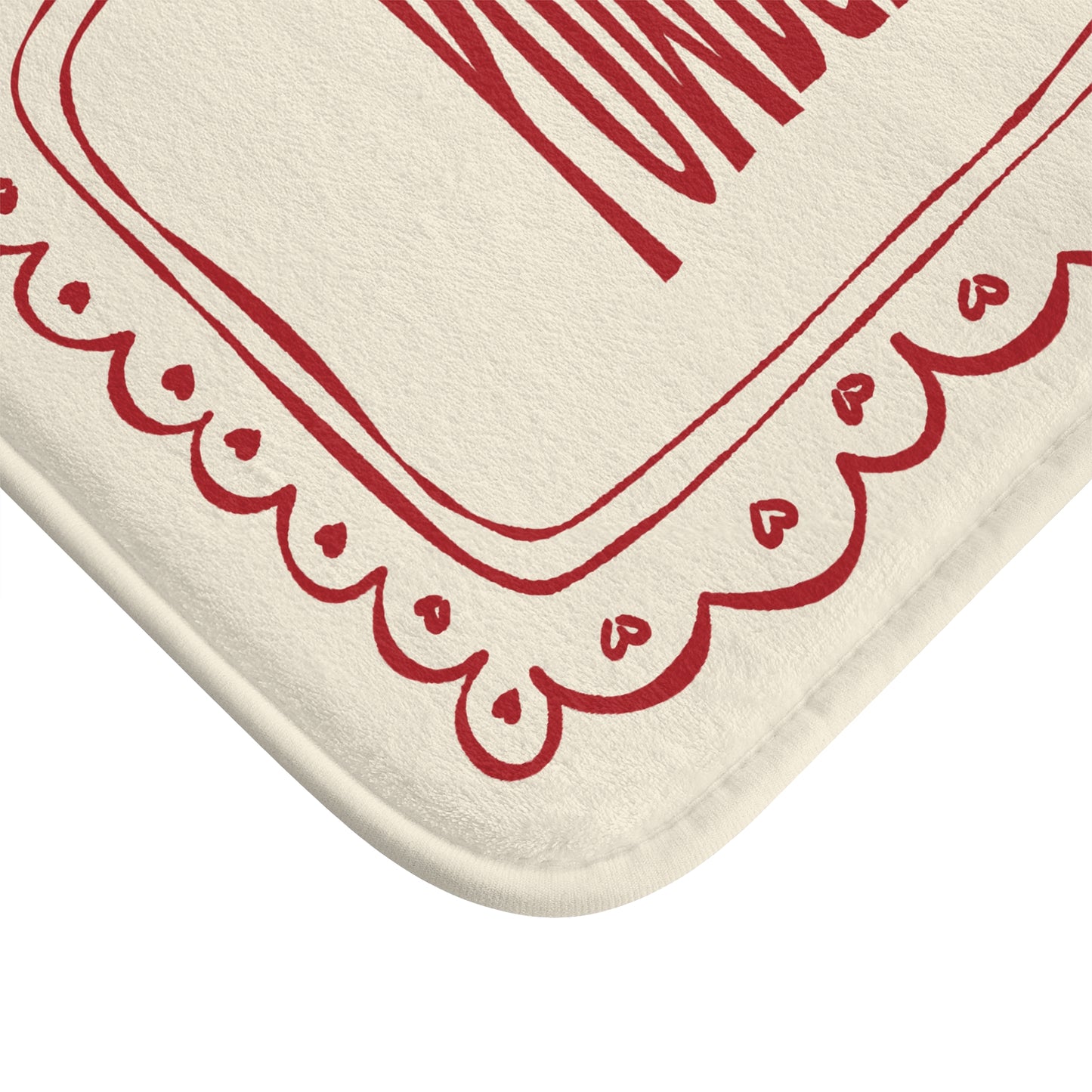Beige bath mat with red decorative border on a white background