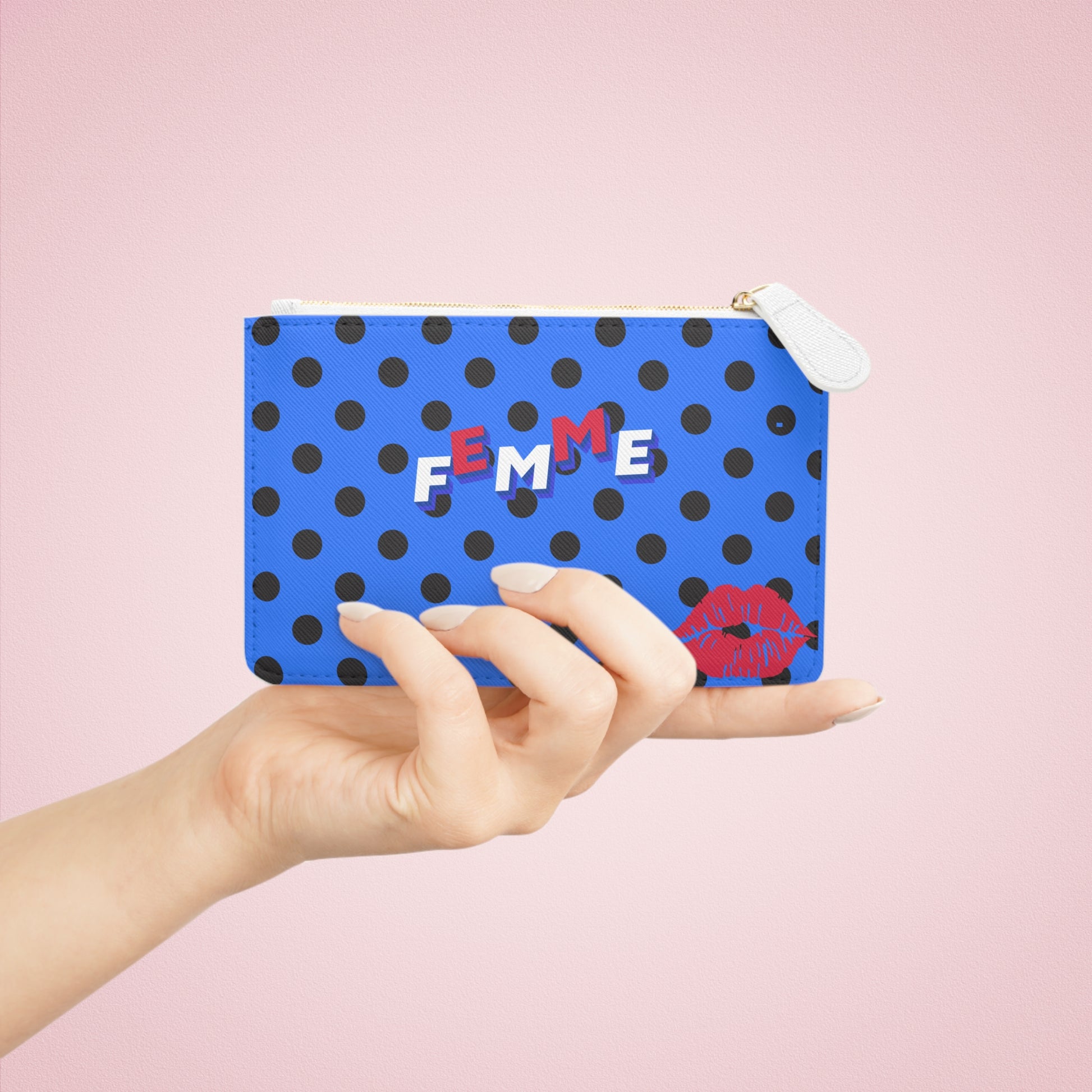 Hand holding a blue pouch with black polka dots and 'FEMME' text on a pink background