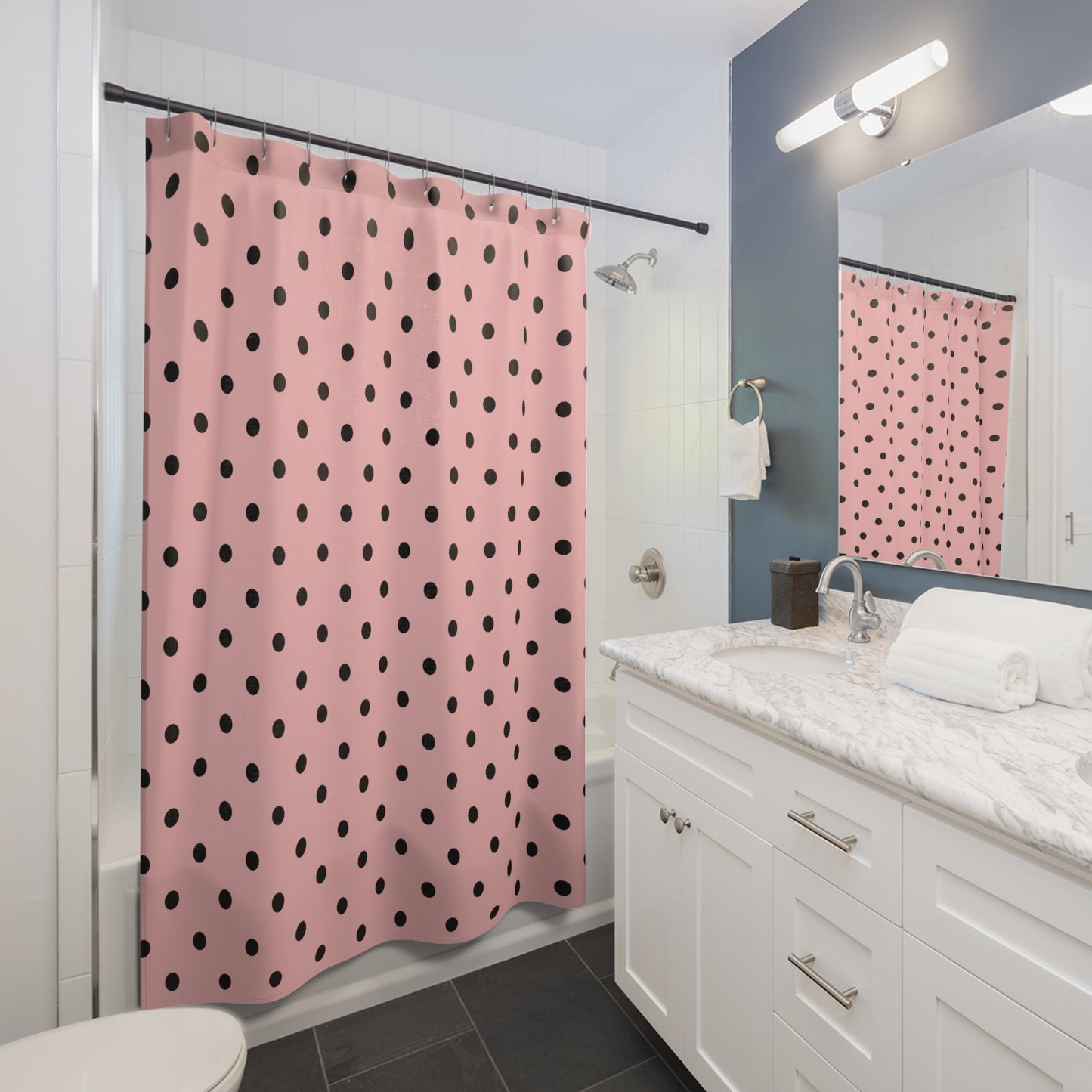 Bathroom with pink shower curtain with black polka dots, white vanity, and mirror.
