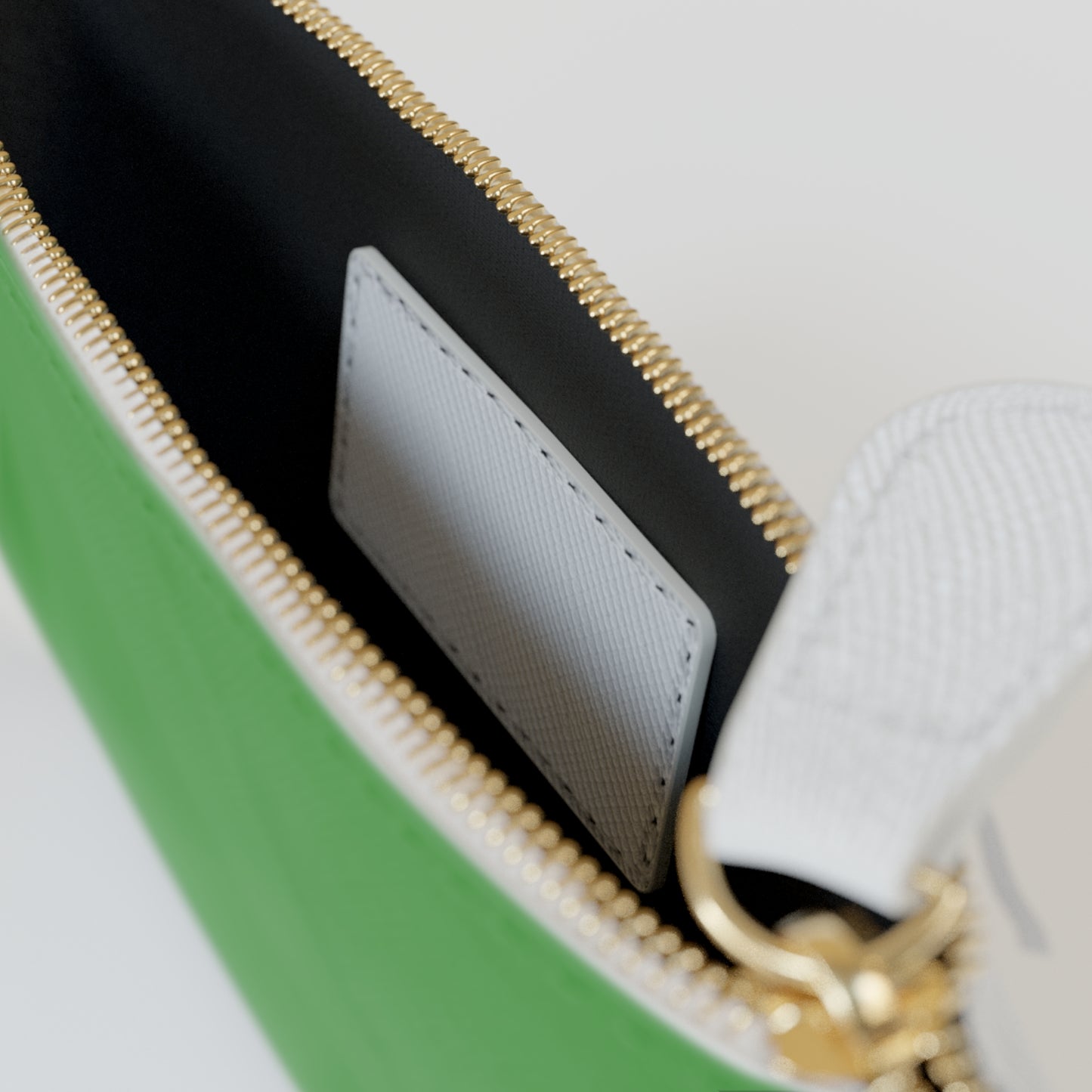 Close-up of a green handbag with gold zipper and white interior.
