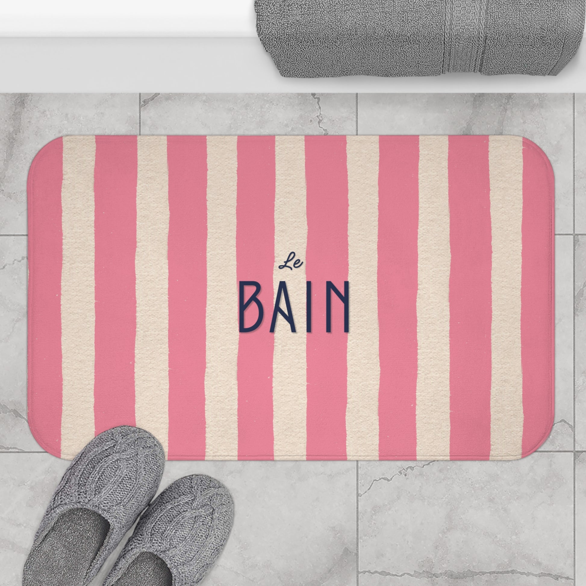 Striped bath mat with 'Le Bain' text on a bathroom floor.