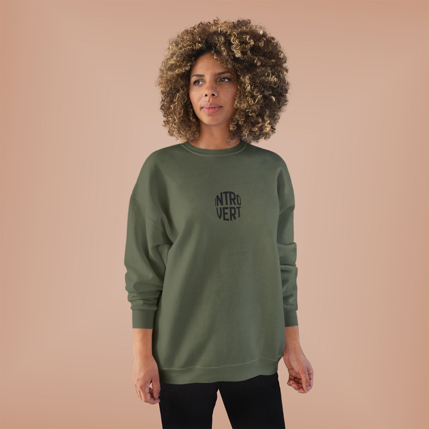 Woman wearing a green sweatshirt with 'INTROVERT' text on a beige background