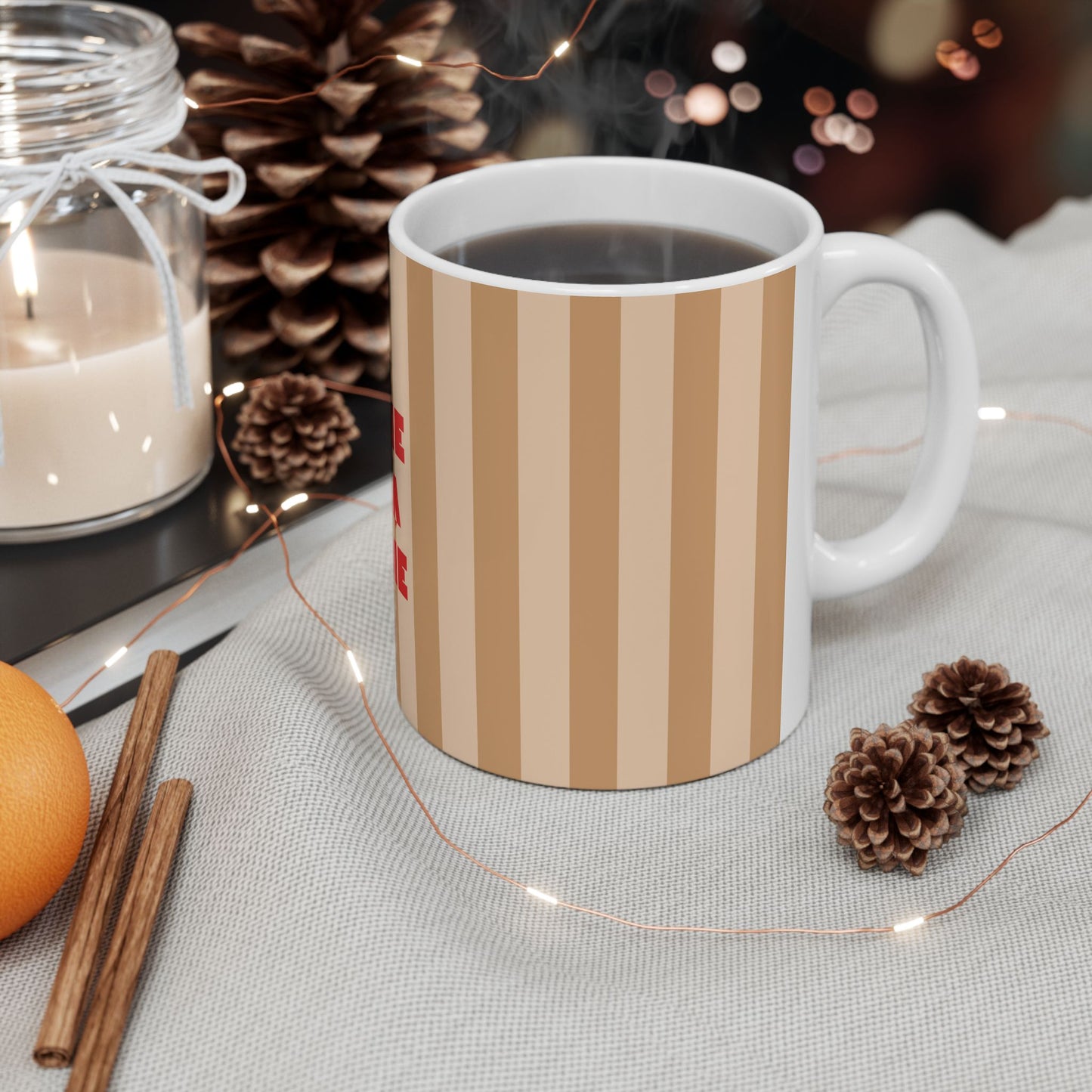 White mug with orange and pink striped design on a table with decorative items