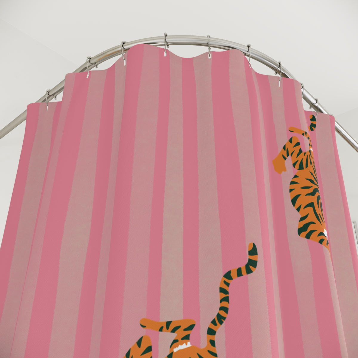 Pink striped shower curtain with cartoon tiger illustrations hanging from a curved silver rod.