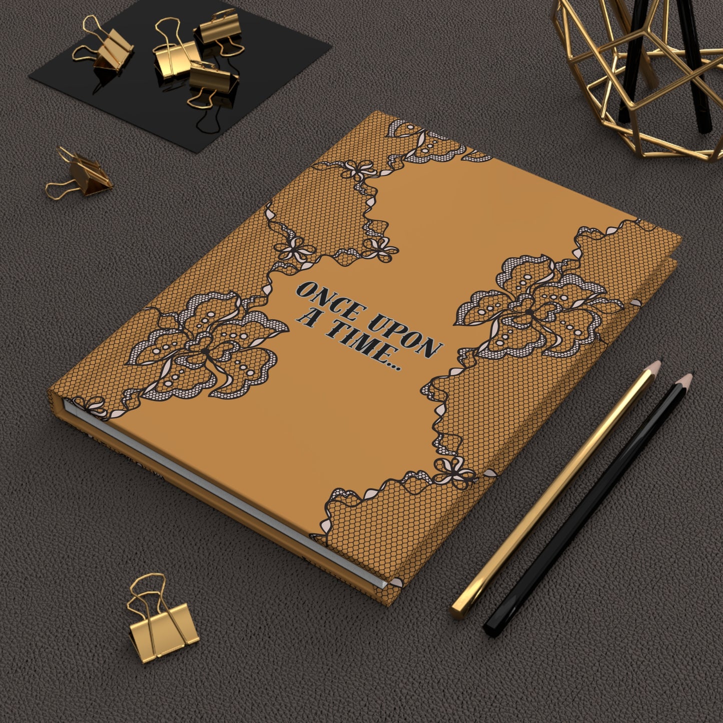 Decorative notebook with lace design and 'Once Upon a Time' text on a dark surface with stationery items.
