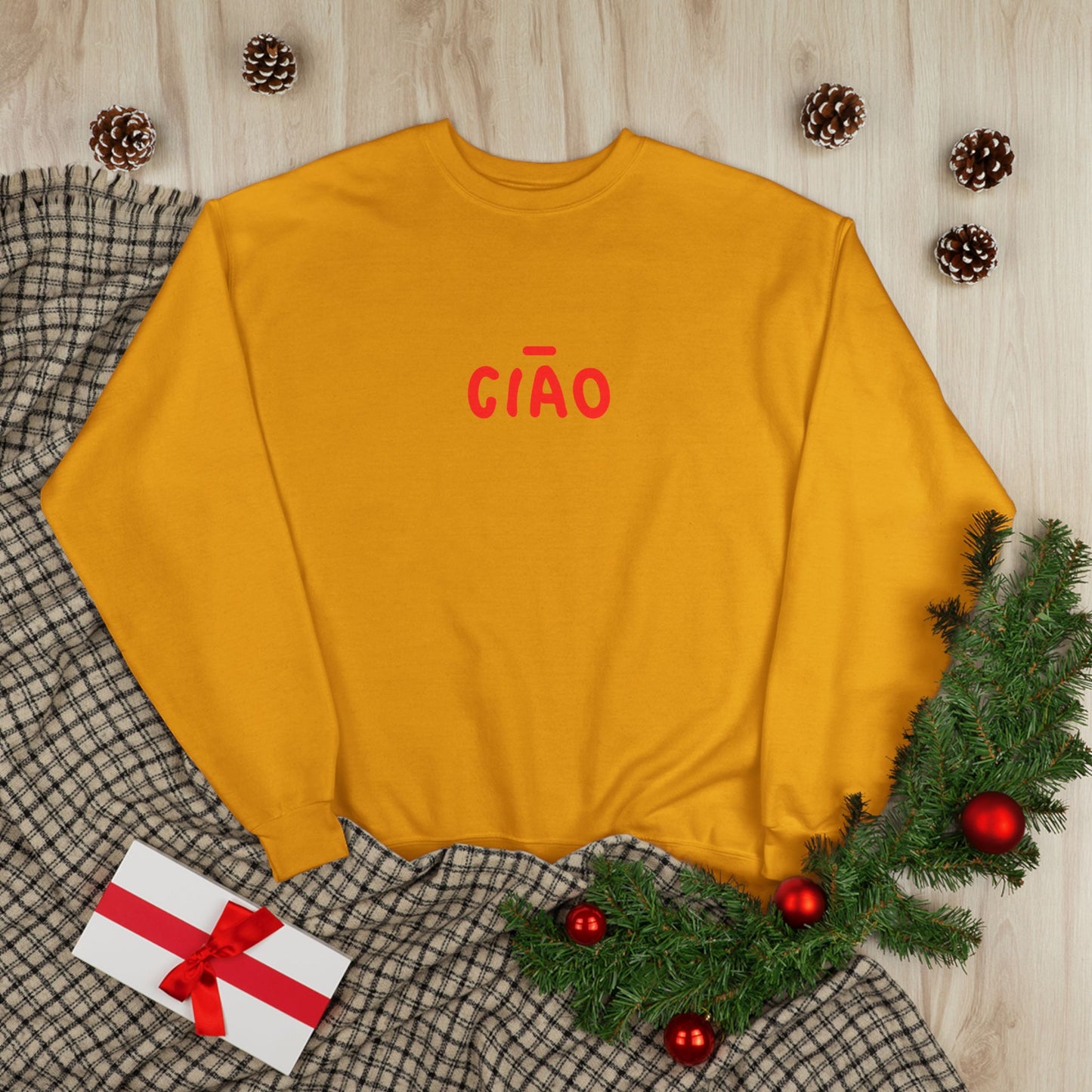 Yellow sweatshirt with 'CIAÓ' text on a checkered fabric background with Christmas decorations.