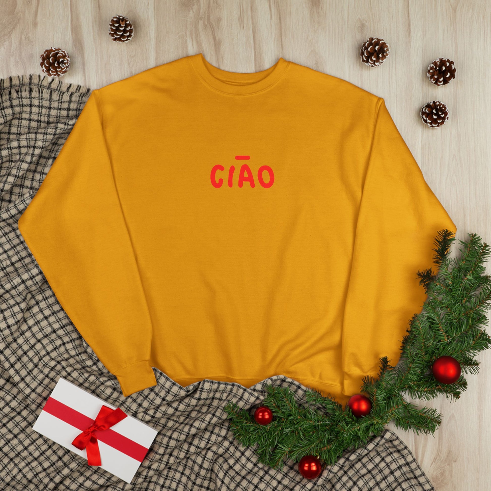 Yellow sweatshirt with 'CIAÓ' text on a checkered fabric background with Christmas decorations.