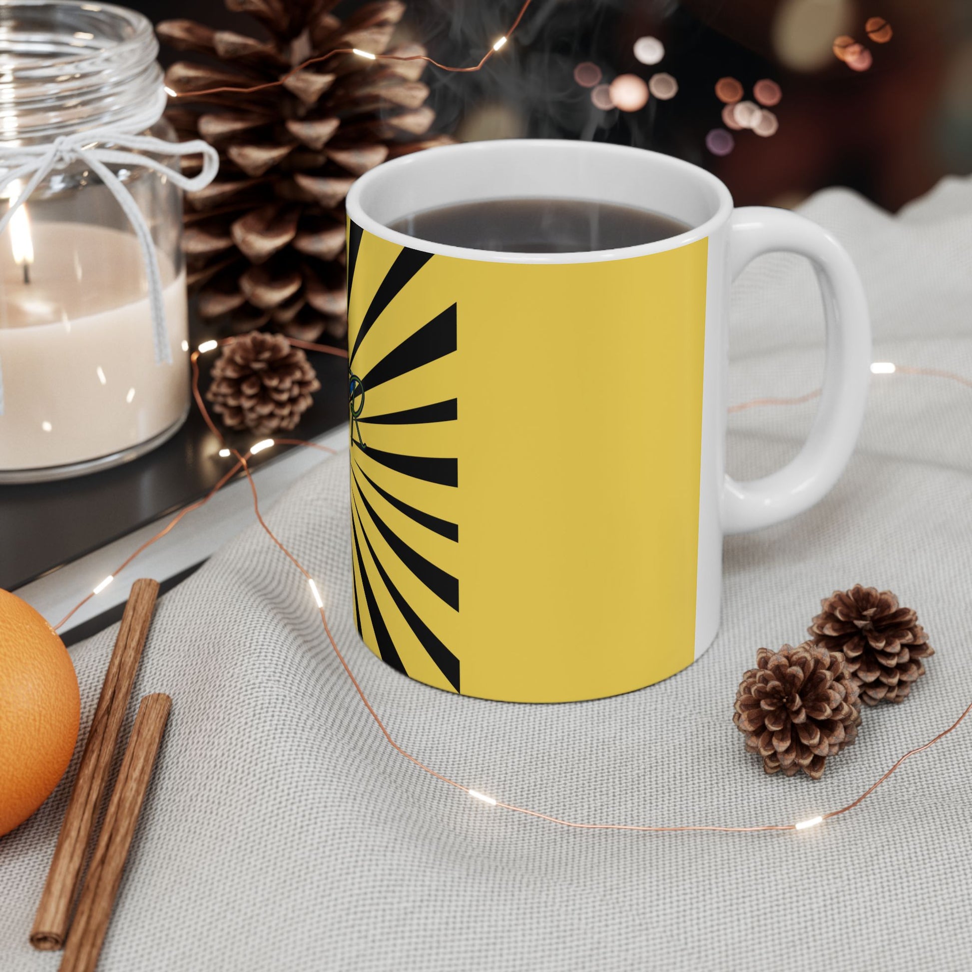 Yellow mug with black design on a table with decorative items