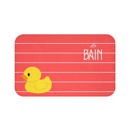 Red bath mat with a yellow rubber duck and 'Le Bain' text on a white background