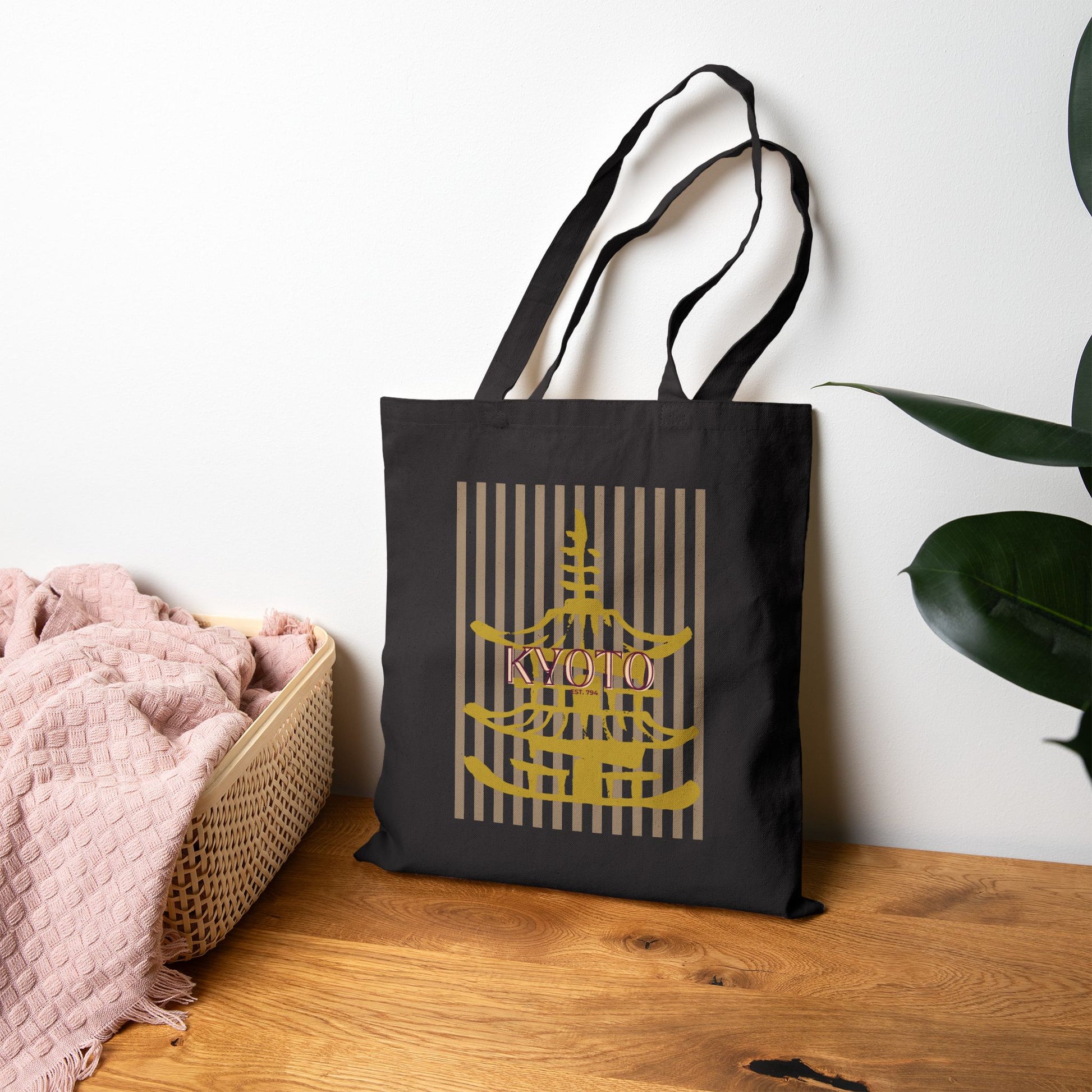 Black tote bag with 'Kyoto' design on a wooden surface with a plant in the background