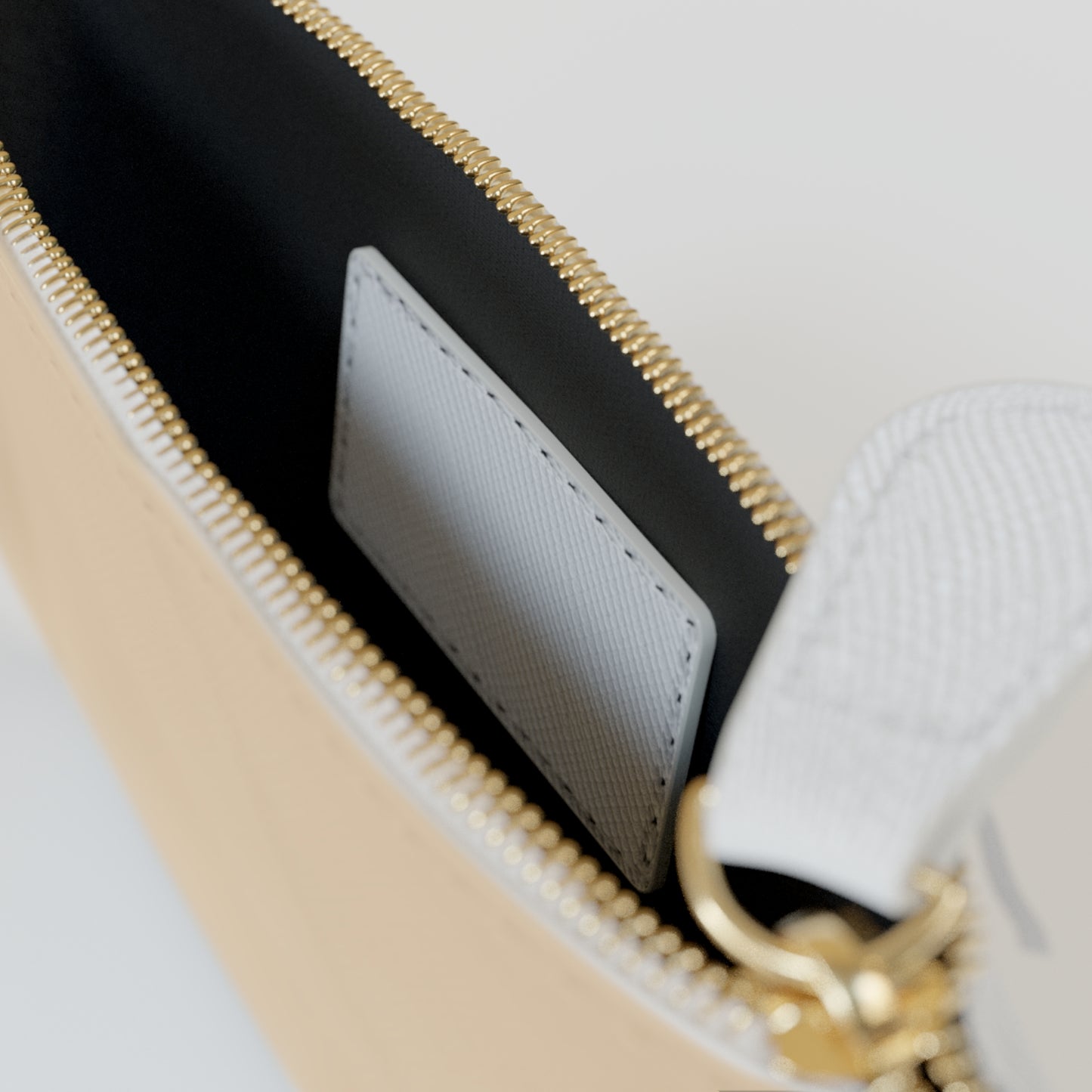 Close-up of a beige and black handbag with gold zipper and chain detail.