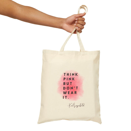 Tote bag with 'Think Pink But Don't Wear It' text and a pink watercolor design, held by a hand against a white background.