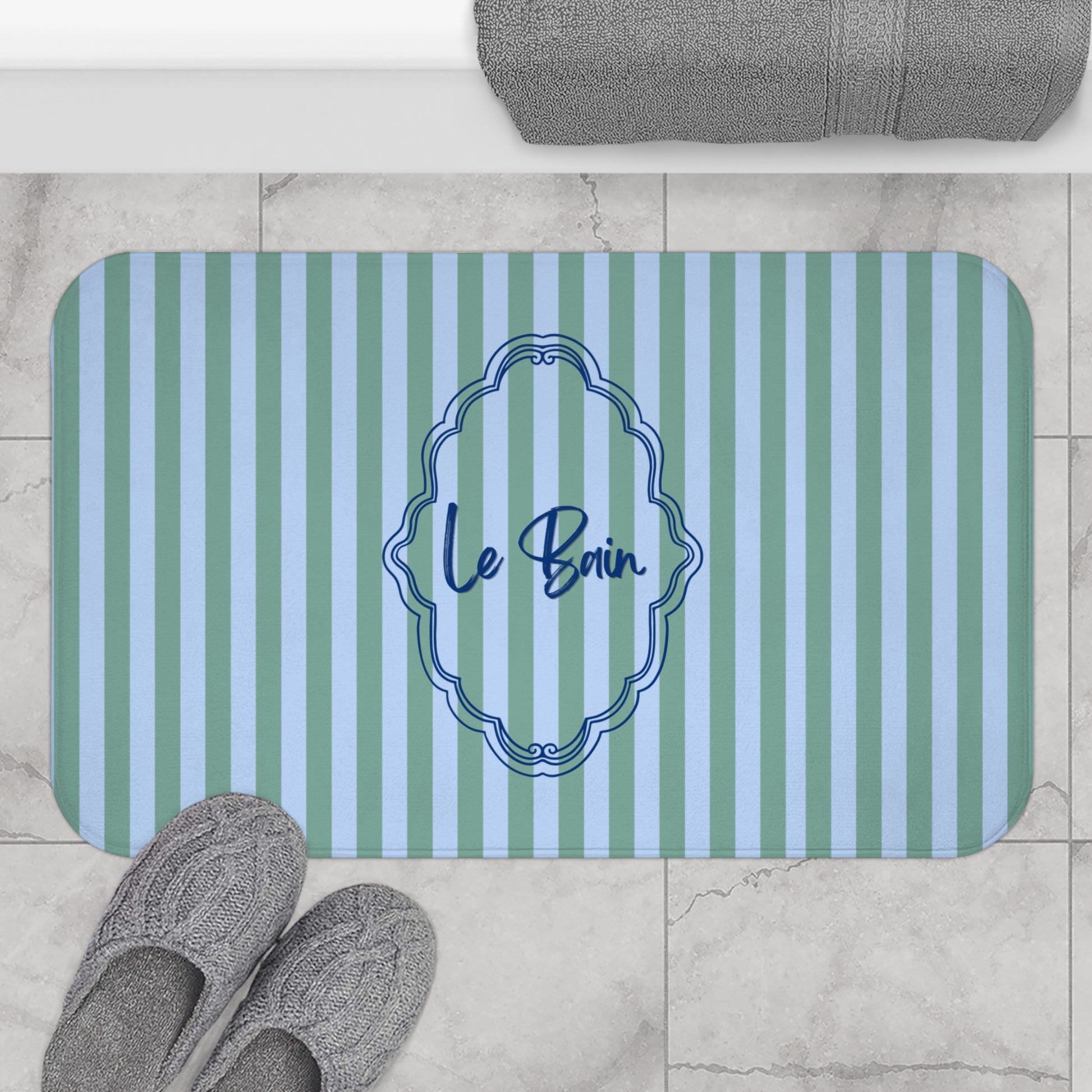 Striped bath mat with 'Le Bain' text on a bathroom floor.