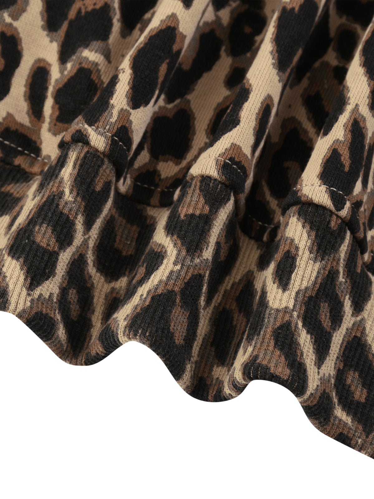 Close-up of a leopard print fabric with a ruffled hem, showing the pattern details in beige, brown, and black.