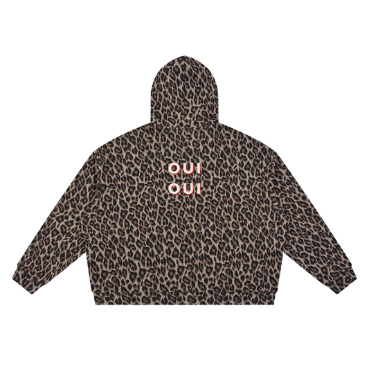 A cropped hoodie with a brown and black leopard print pattern, featuring the word 'OUI OUI' printed in white with a red outline on the back.