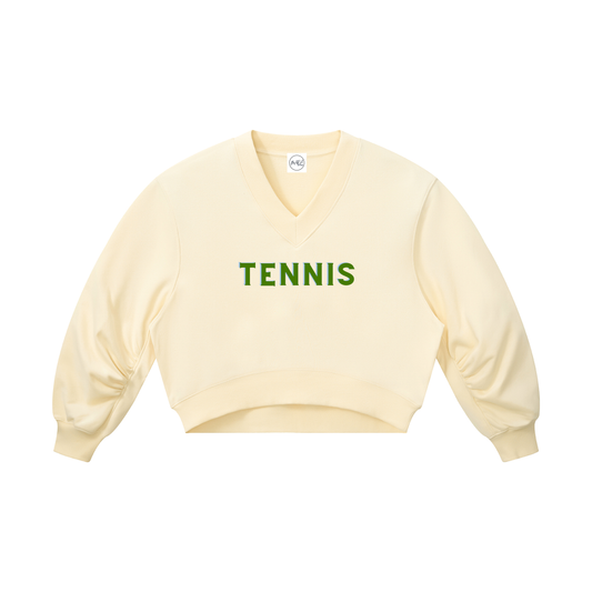 A pale cream-colored long-sleeve V-neck sweatshirt with 'TENNIS' printed in green across the chest, displayed flat against a solid white background.